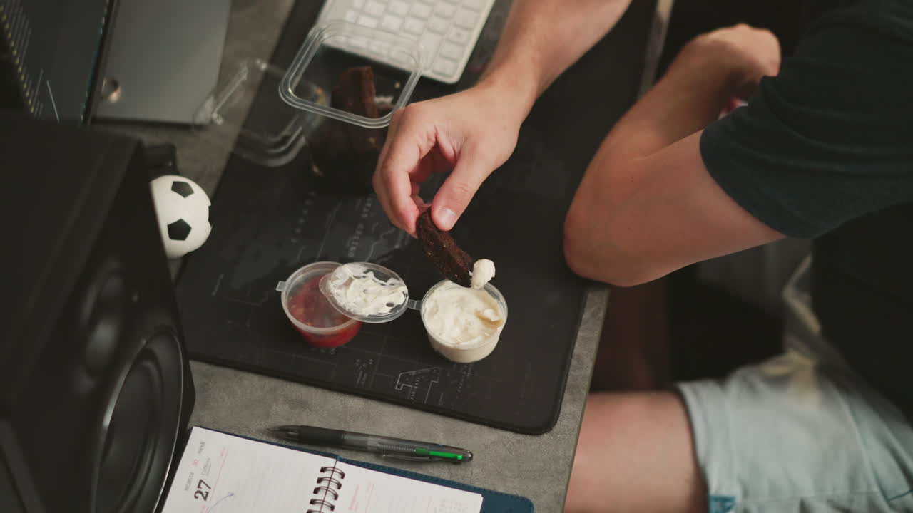 Person eating bread with dipping sauce at a desk