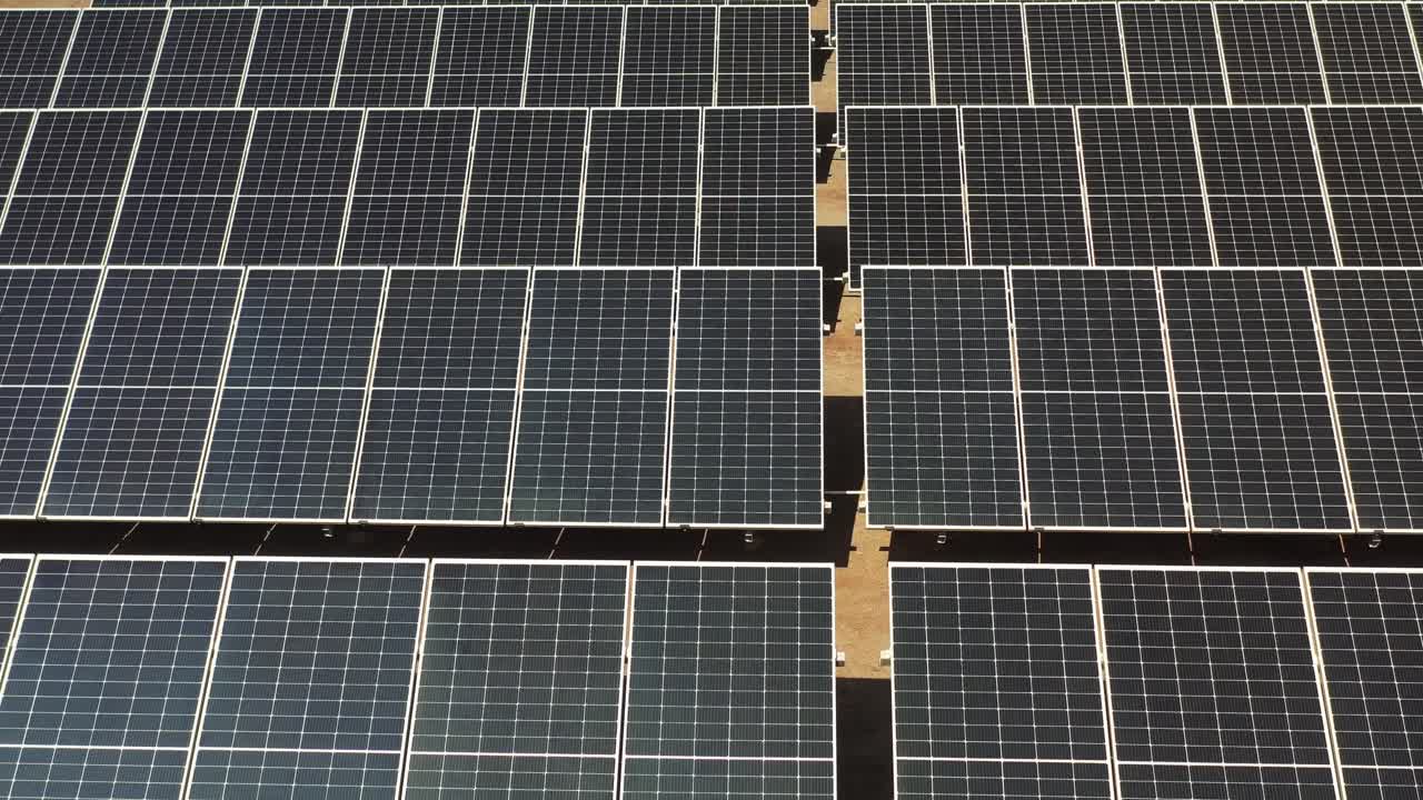 aerial close up view of solar panels in photovoltaic farm. Solar power plant with sun reflected.4k video