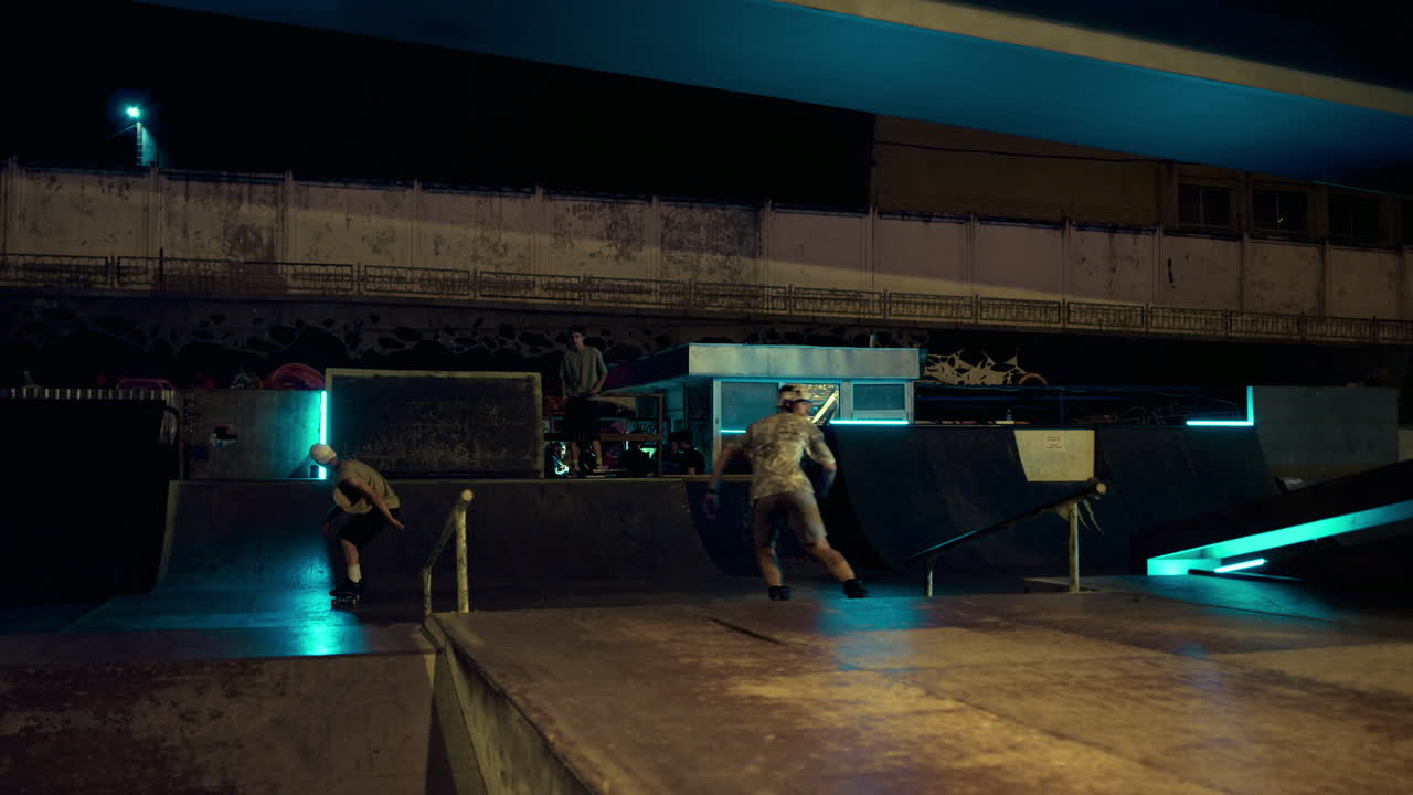 amigos extremos realizando una acrobacia de salto en el carril en el parque de patinaje nocturno. concepto deportivo