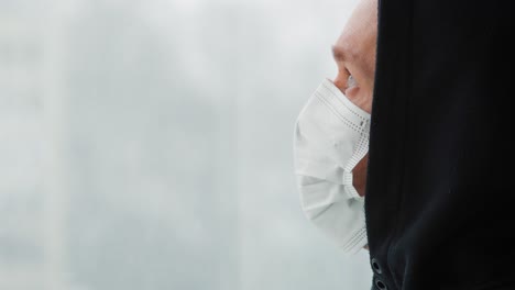 man with a face mask looking out of the window