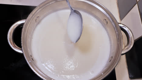 man gently stirs thickening semolina porridge in a pot during slow zoom shot