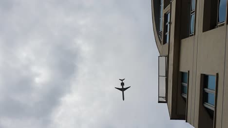 着陸飛行機が曇りの日に街の上空、真下を飛ぶ