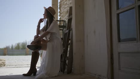 woman in a boho style dress sitting on a porch