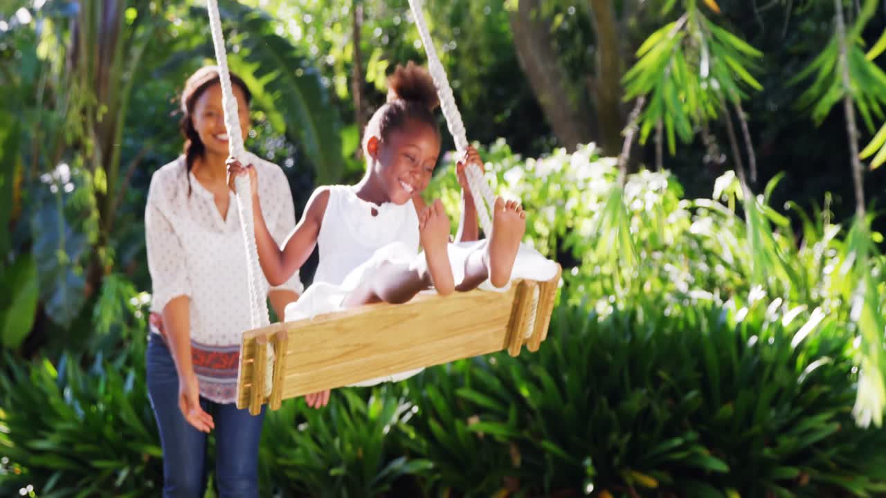 una niña balanceándose con su madre