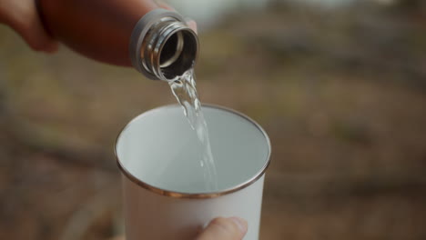 hands of woman pouring water in mug