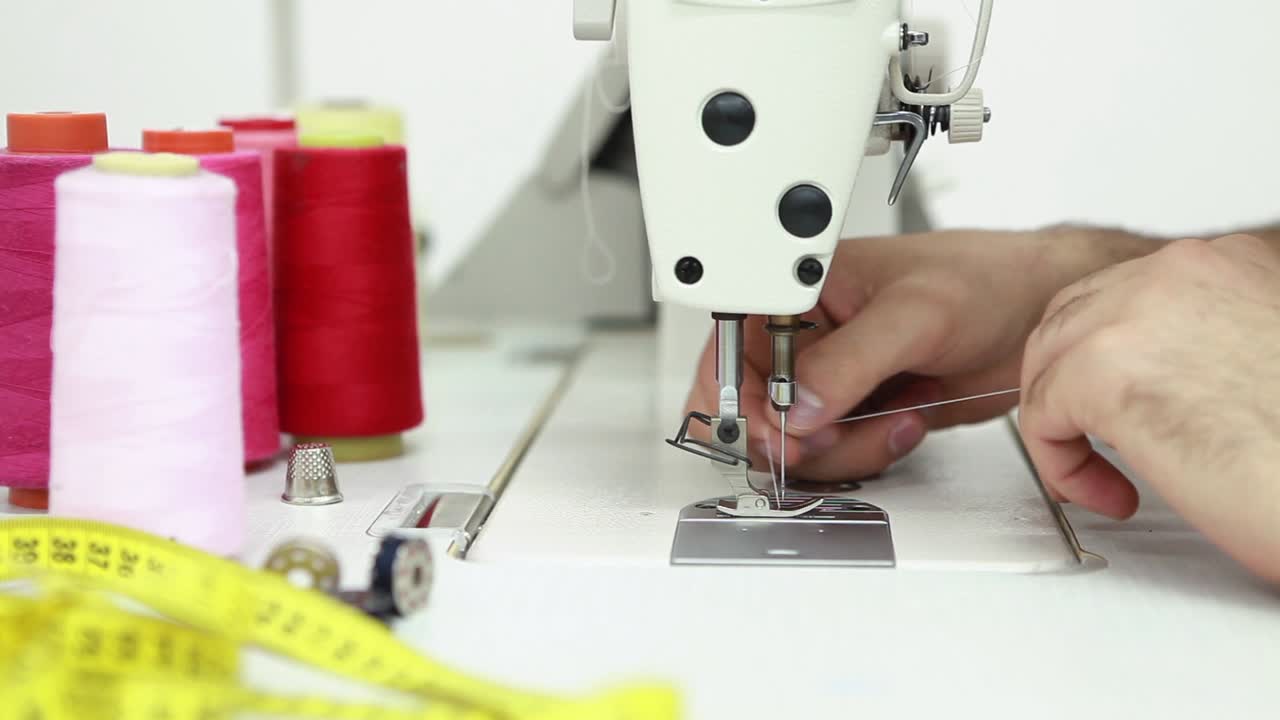 primer plano de la aguja de la máquina de coser se mueve rápidamente hacia arriba y hacia abajo