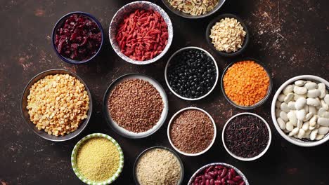 various superfoods in smal bowls on dark rusty background