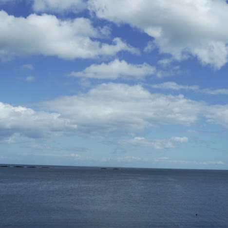 Cielo-Azul-Con-Nubes-Y-Mar-Desde-Un-Coche-En-Movimiento