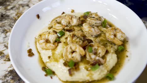 sprinkling chopped green onions on a plate of shrimp and grits