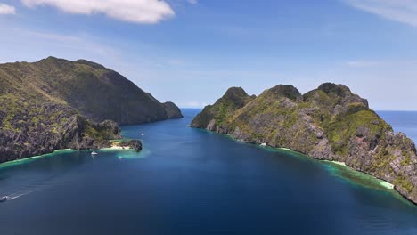 aerial view of star beach on tapiutan island in the philippines with deep blue waters, cliffs, and boats anchored near coral reefs along the lush coastline under clear blue skies