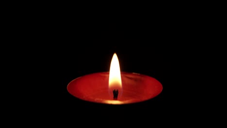 igniting floating candle flame on black background, windy conditions extinguishing, macro shot