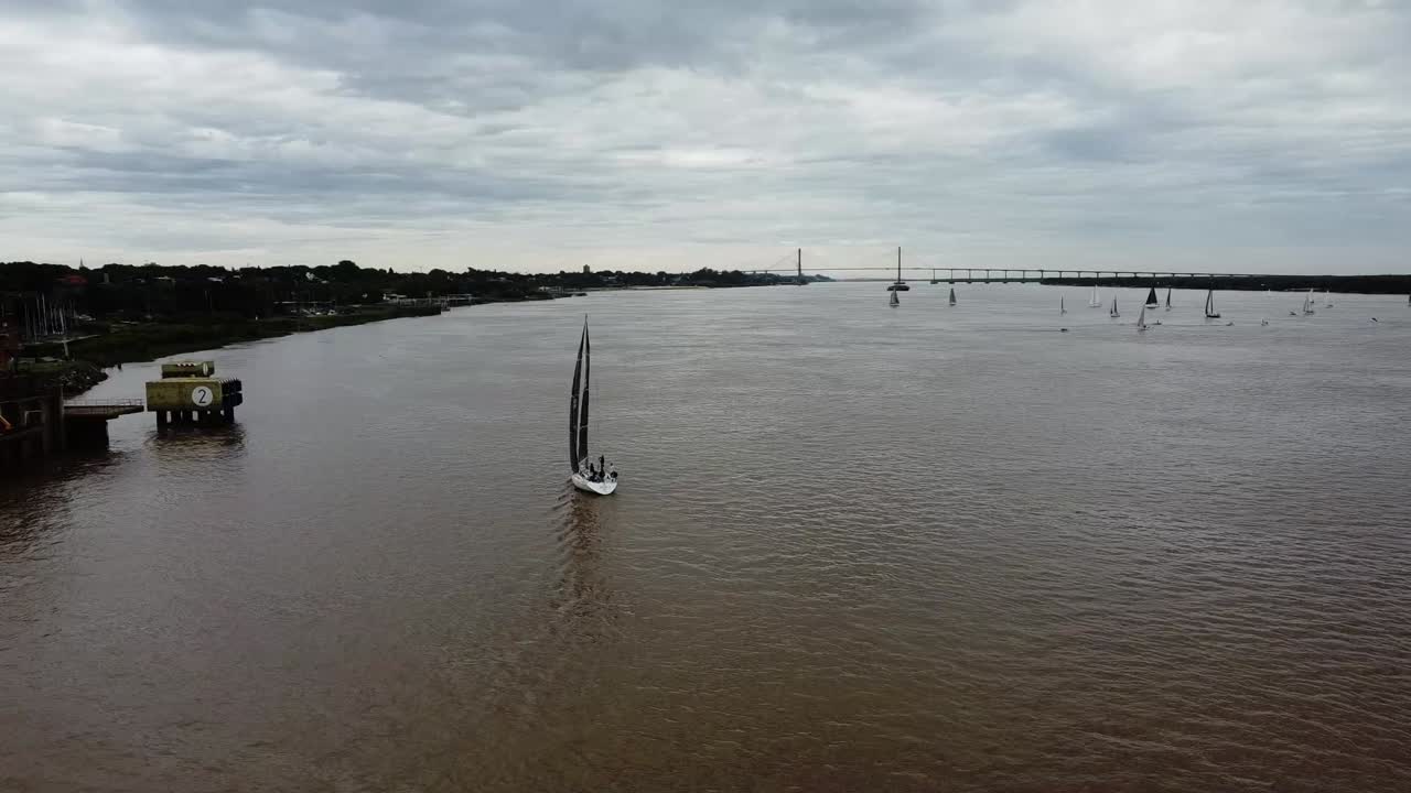 vista orbital desde el dron del velero navegando por el río paraná con el puente al fondo