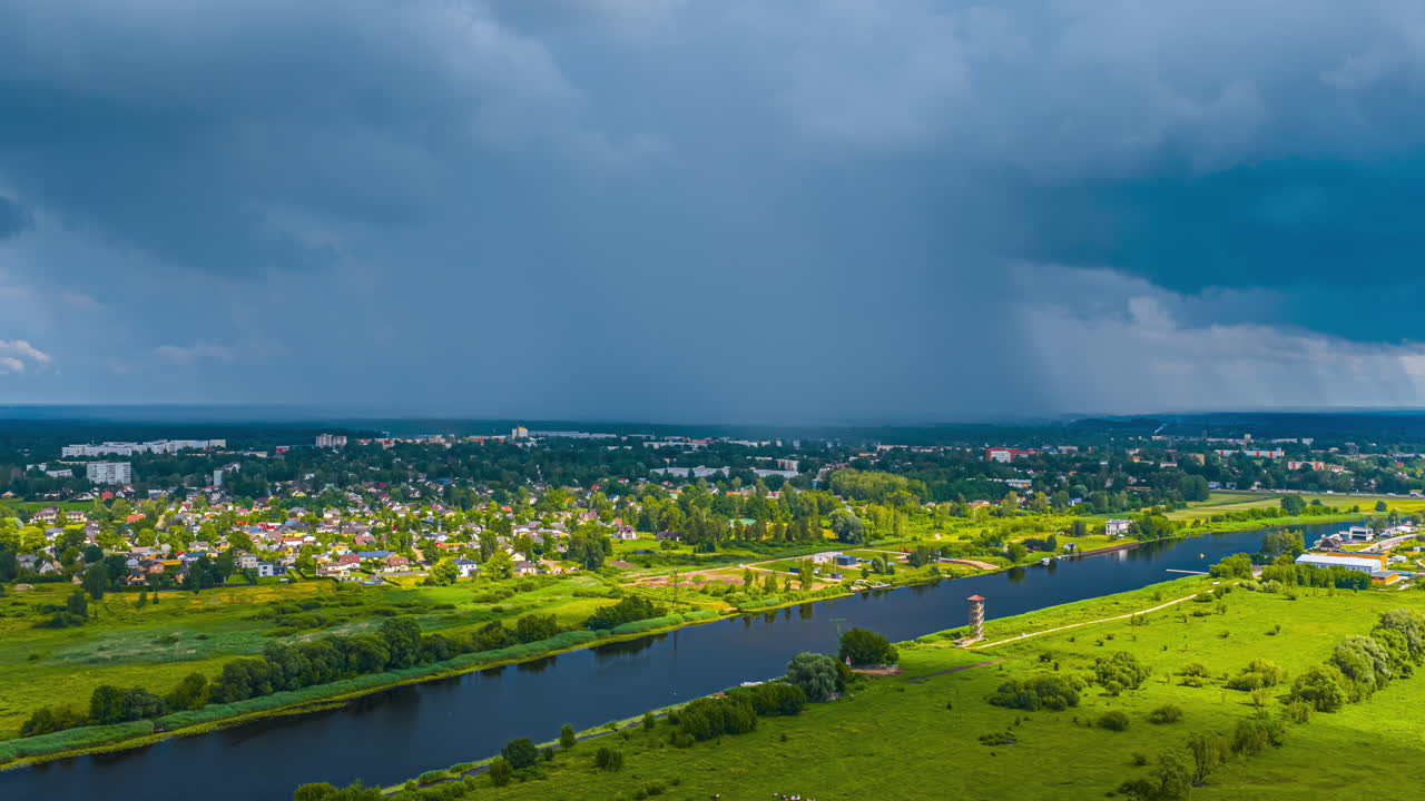 Storm clouds over river, greenery, and city skyline in a timelapse