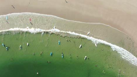 Surfers-and-colorful-surfboards-in-Hong-Kong-beach,-Aerial-view