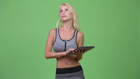 young happy beautiful woman thinking while using digital tablet ready for gym