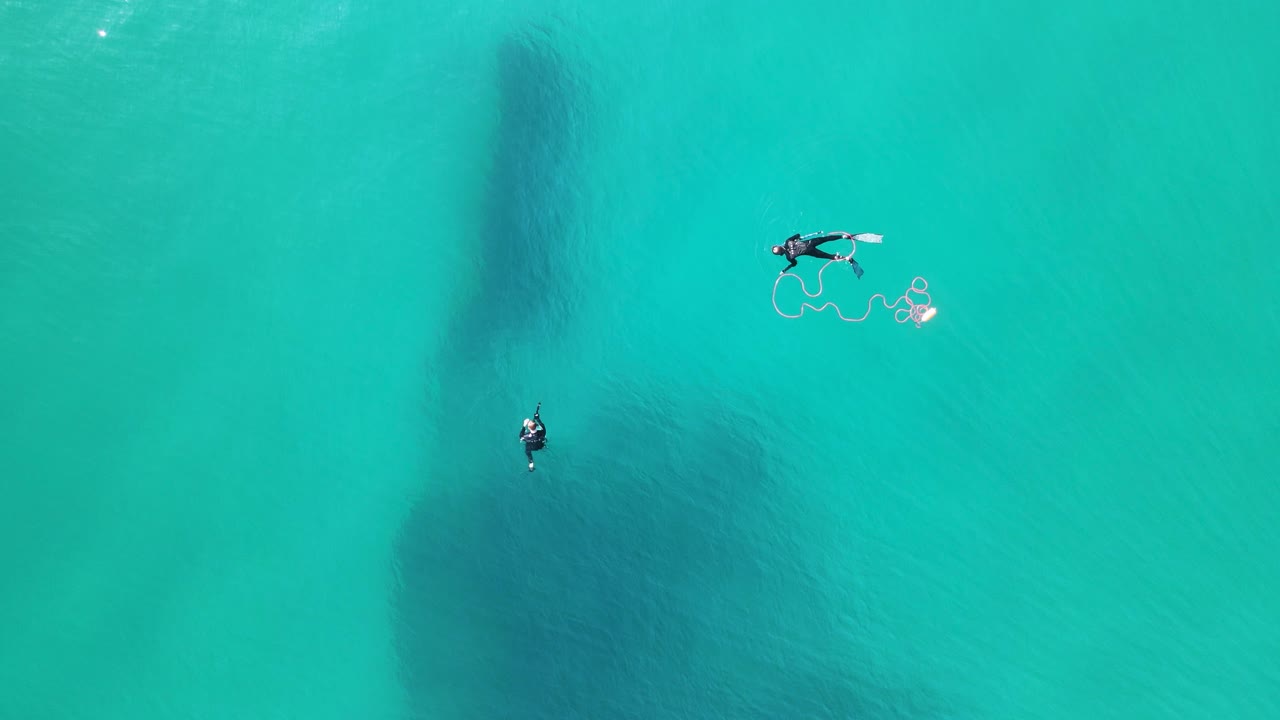 스피어피싱 하는 사람 들 은 침몰 한 선박 잔해 위 에 있는 파란 물 에 떠 있다
