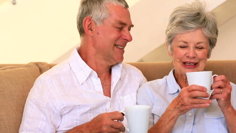 Senior-couple-sitting-on-couch-having-coffee