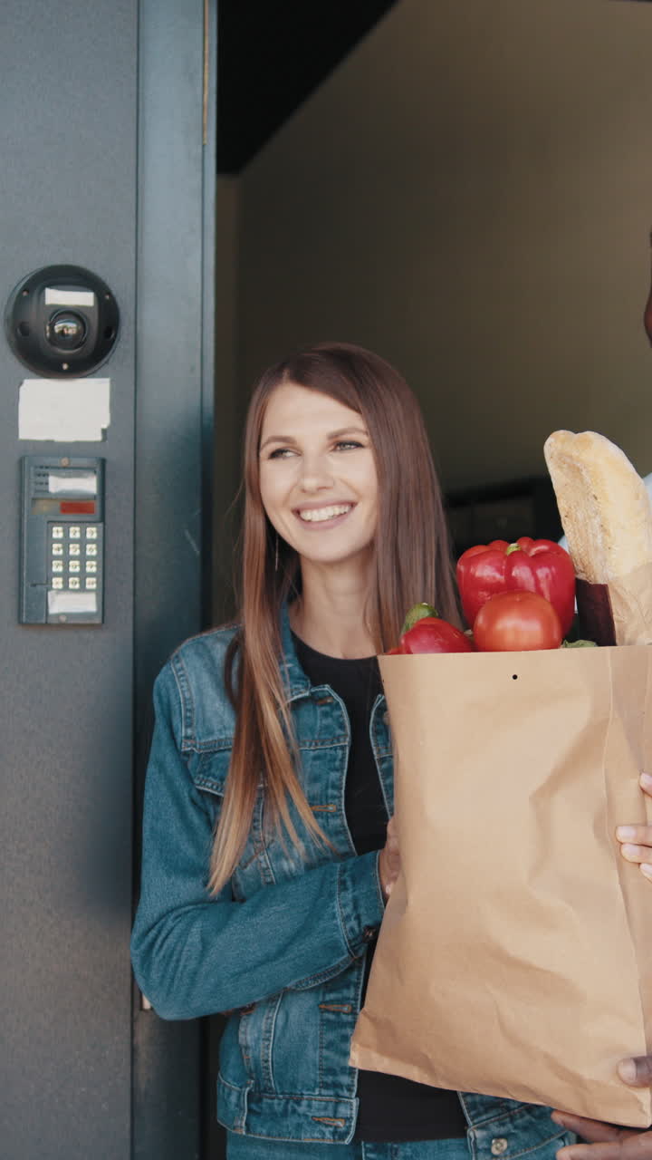 A man delivers groceries to a smiling woman at her doorstep