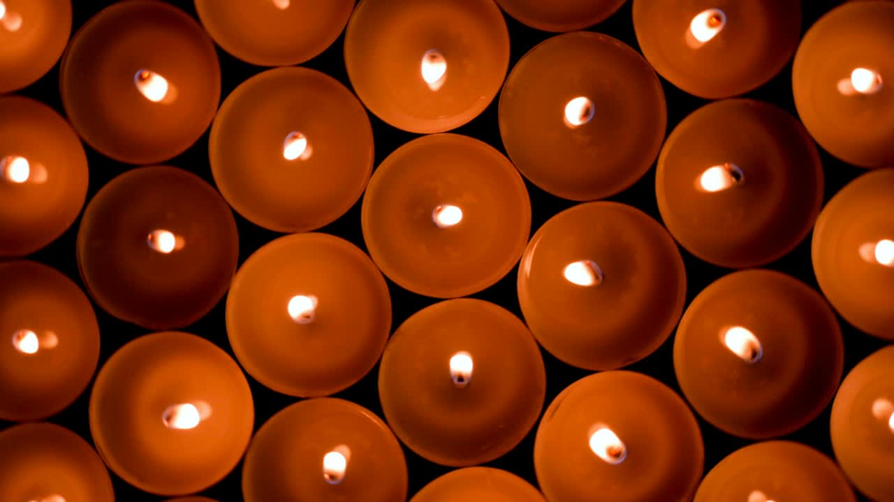 многие горящие круглые маленькие свечи с отражениями горят в темноте. огонь на заднем плане.