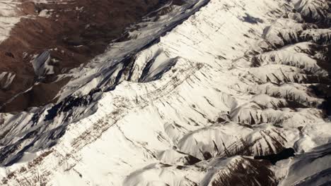 Vista-Aérea-Desde-Un-Avión-Del-Paisaje-Montañoso-De-Irán-Cubierto-De-Nieve-En-Medio-Oriente