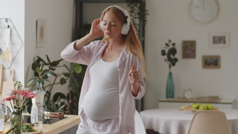 pregnant woman dancing to music in kitchen