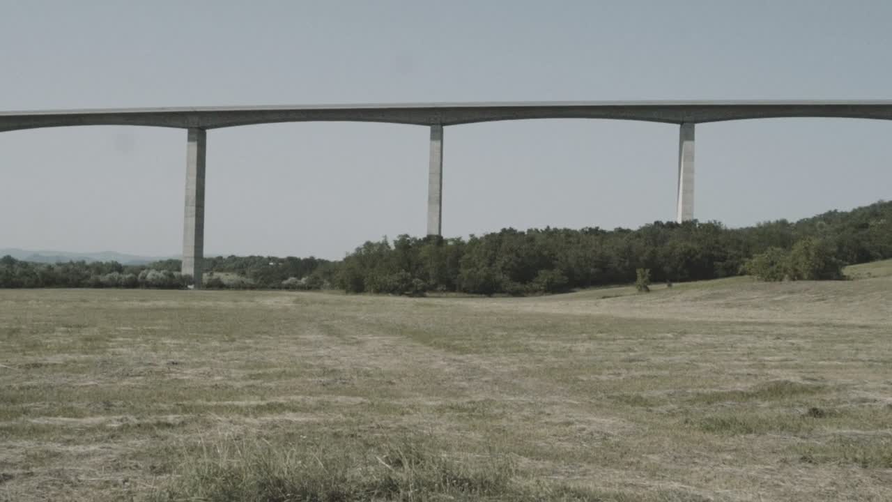 Panning view from a highway bridge and its huge columns.