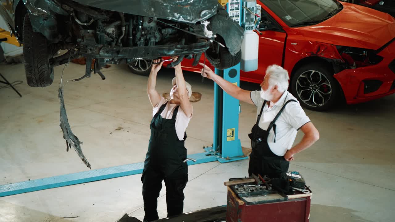 trabajadores mecánicos de automóviles que trabajan debajo de la máquina de elevación de automóviles en el garaje.