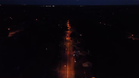 car on lighting straight street at night. american suburb neighborhood at midnight. aerial birds eye. calm peaceful city of usa. drone wide shot.