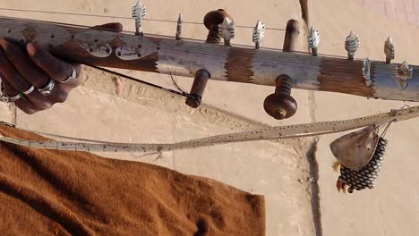 artist playing traditional sarangi from different angle at day