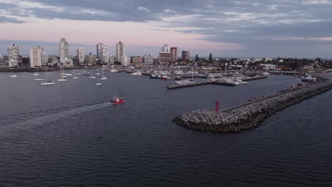 Vista-Aérea-Del-Barco-Pesquero-Que-Llega-Al-Puerto-De-Punta-Del-Este-Con-Horizonte-De-Fondo-Al-Atardecer---Uruguay,-Sudamérica