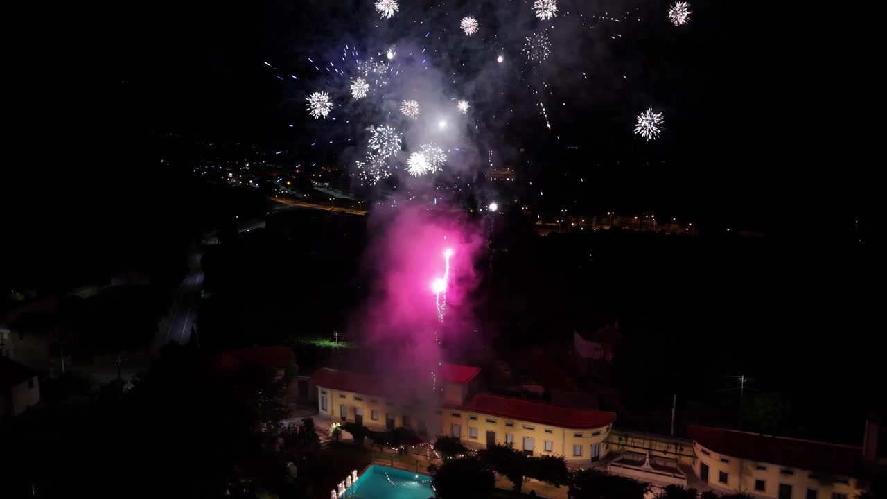 Aerea - fuochi d'artificio che si innalzano sopra una villa e una piscina illuminata durante una celebrazione notturna