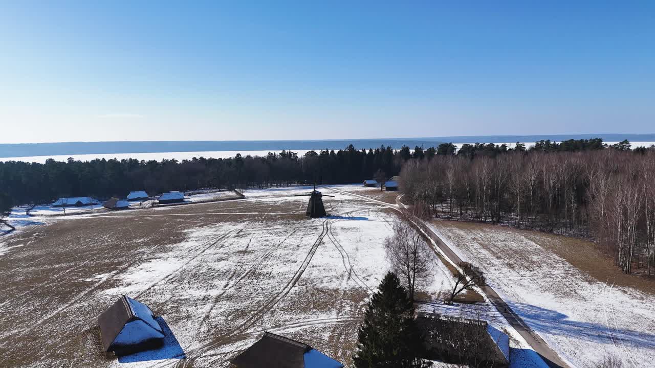Wooden millhouse near village in winter, aerial panoramic view