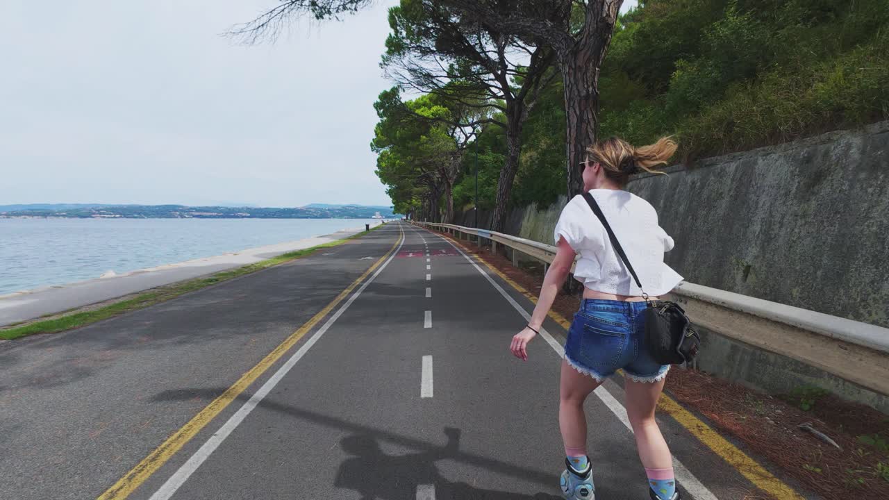Caucasian woman rollerblading on coastal path between Koper and Izola, Slovenia, tracking shot