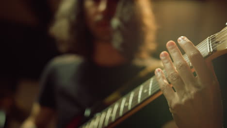 male musician playing guitar in studio. man hand pinching chords indoor.