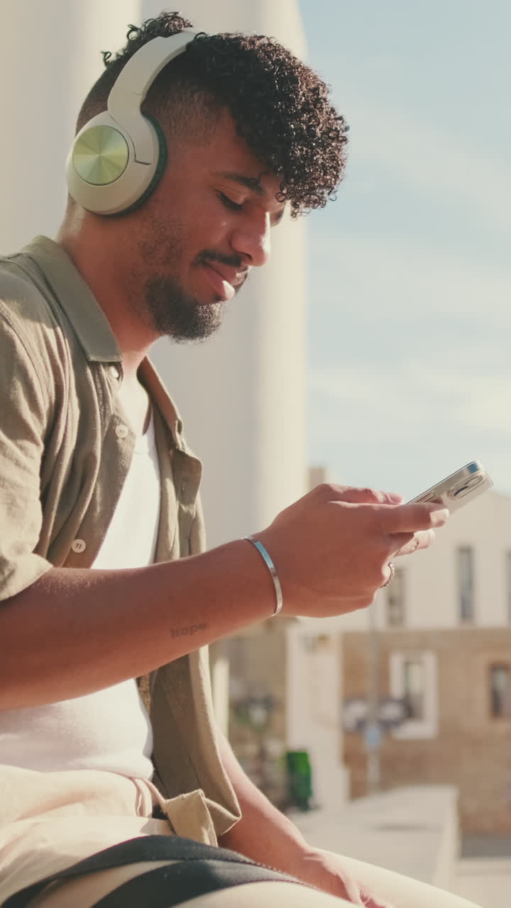 Young man using smartphone with headphones outdoors