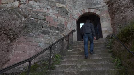 a man walking up stone steps to an archway in an ancient brick building, castle or fortress