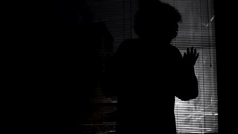 scared lonely woman looking at storm with wind through a windows blinds at night, looking outdoors