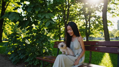 young woman playing with a cute kitten on a park bench