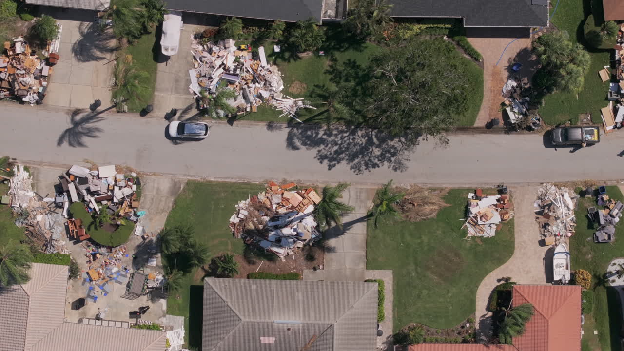 Top down rows of Florida neighborhood with piles of trash and debris flooded from Hurricane Milton aftermath clean up effort