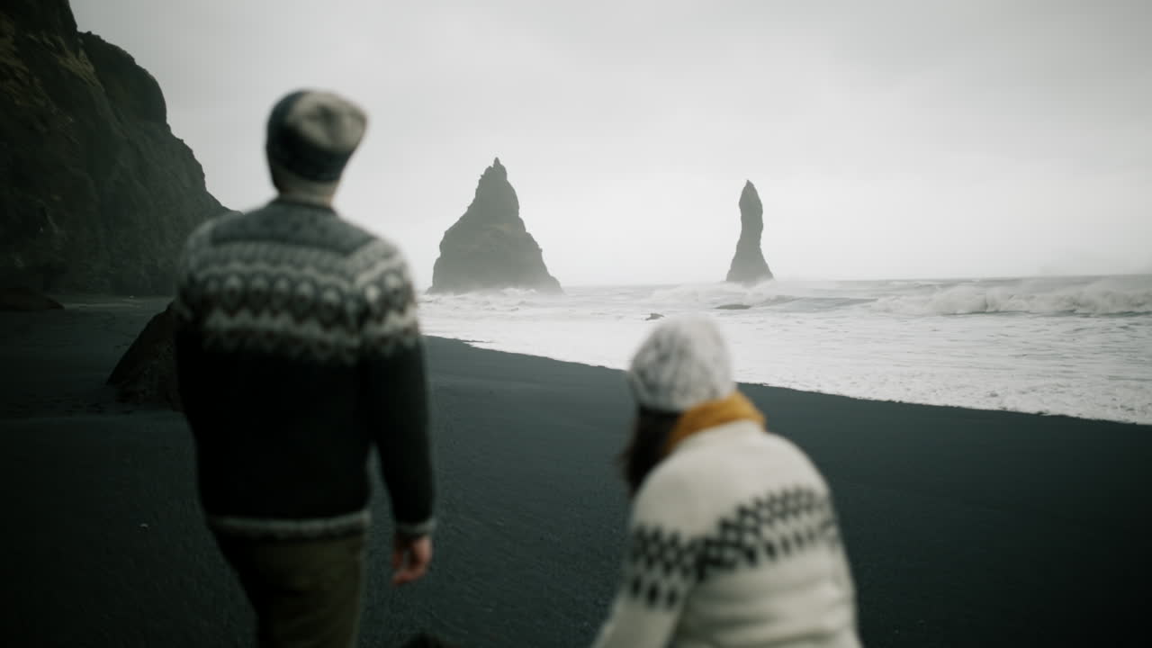 Couple walking on a black sand beach in Iceland