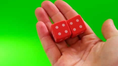 suerte y éxito concepto.juegos de azar. juegos de mesa. partido, mismos números. cubos rojos en las manos sobre un fondo verde brillante.