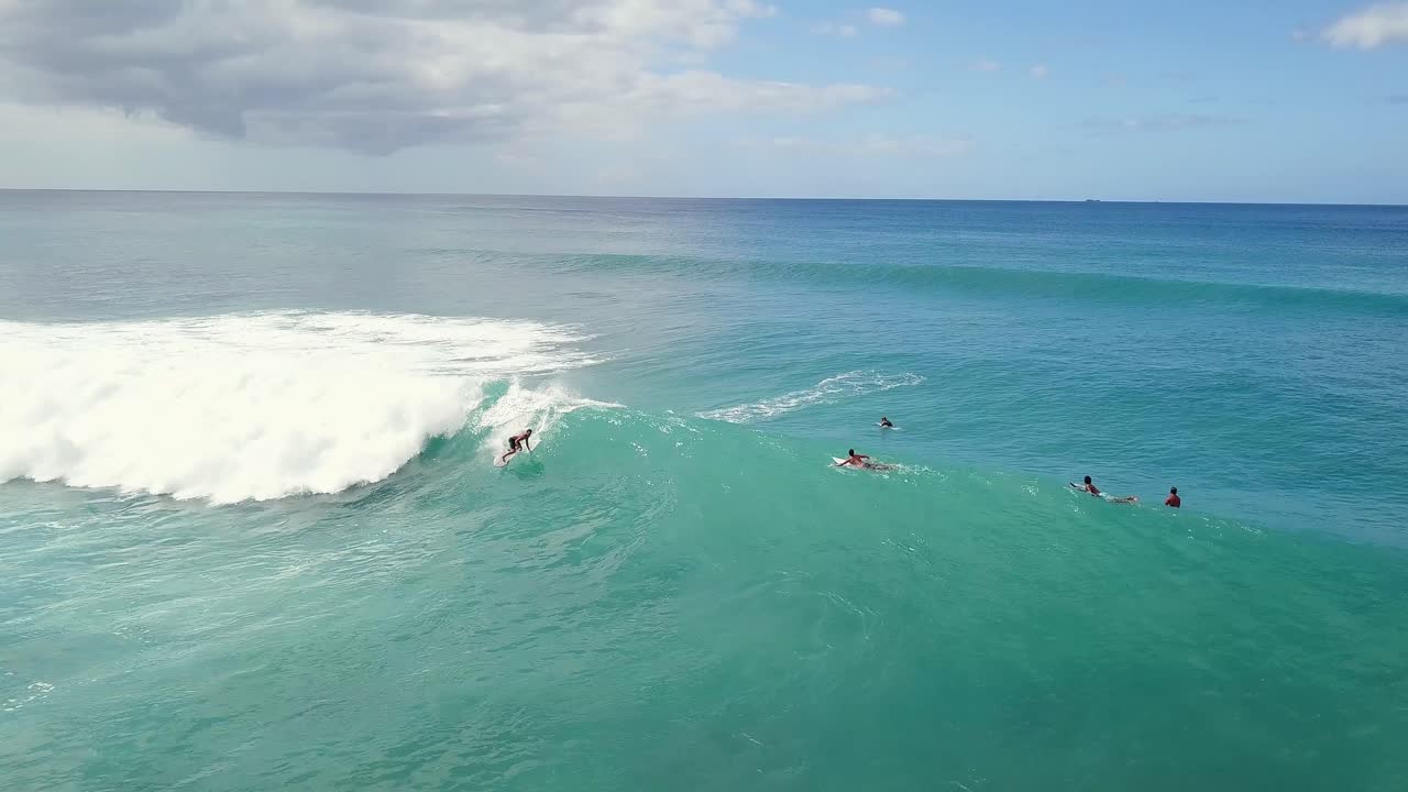 Surfer paddles onto large wave spraying and carving reverse aerial tracking