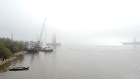 a boat navigates the river on a foggy winter morning along the rosario coastline, creating a serene and mysterious atmosphere.