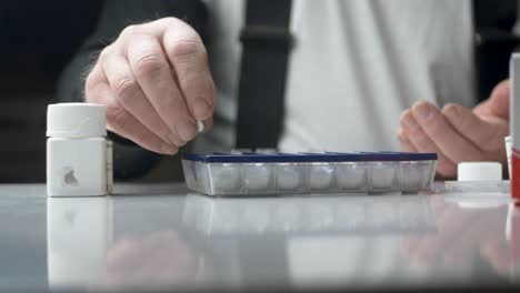 old man dividing his weekly pills by the medicine pill case - static close up shot