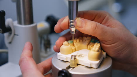 manufacturing the model of denture. close up. technician's hands operating the machine tool for denture production.