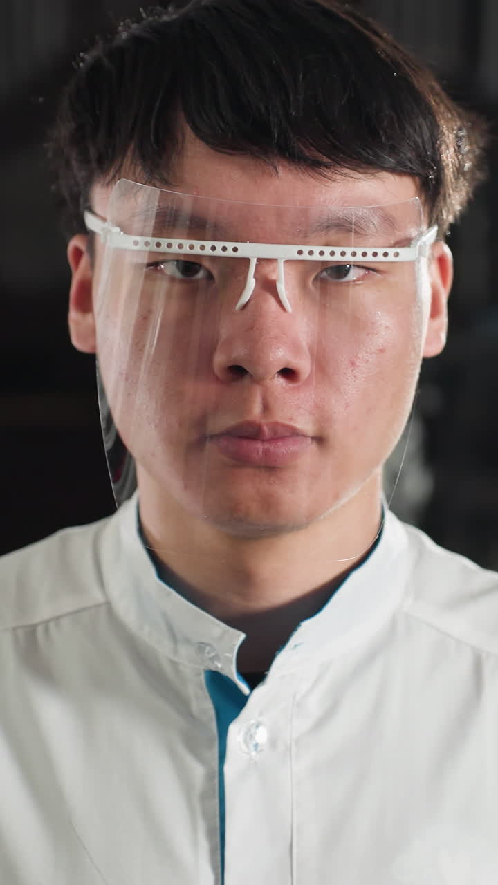 primer plano de un ingeniero químico en bata de laboratorio ajustando gafas de protección en un taller de automóviles iluminado, expresión enfocada, fondo de características de equipo verde luz y entorno industrial
