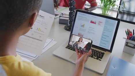 mujer de negocios afroamericana que usa un teléfono inteligente para una videollamada con un colega de negocios biracial