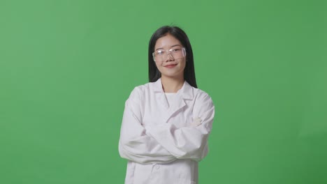 asian woman scientist smiling and crossing her arms while standing on the green screen background in the laboratory