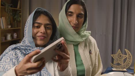 Madre-E-Hija-Posando-Para-Selfie-Alrededor-De-La-Mesa-De-La-Familia-Musulmana-En-Casa-Comiendo-Comida-Iftar-Rompiendo-El-Ayuno-Diario-Durante-El-Ramadán