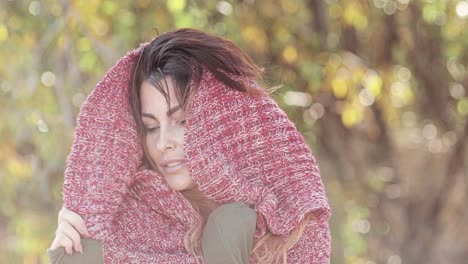 portrait of a beautiful brunette fashion model posing outdoors wearing a knit scarf